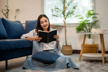 A woman is sitting on the floor reading a book