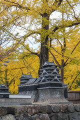 Miniature Japanese Castle Surrounded by Vibrant Autumn Ginkgo Trees"