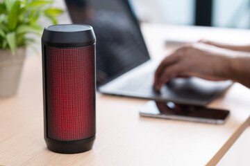 Business man enjoys his favorite tunes while scrolling through his phone.The speaker,on the desk,...