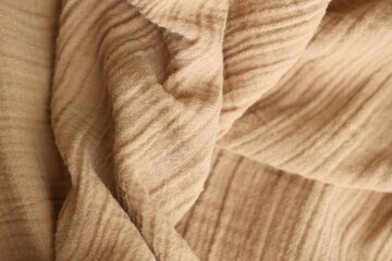 Texture of crumpled linen fabric under natural light in peach fuzz color