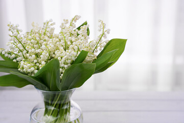 A bouquet of fresh lilies of the valley in a glass vase. Close-up. Selective focus.
