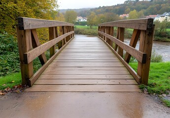Obraz premium A wooden bridge spans a calm river, surrounded by lush greenery and autumn trees under a cloudy sky.