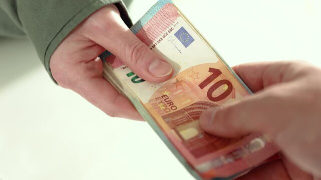 Close-up of two people exchanging a stack of euro banknotes, symbolizing financial transactions, business payments, loans, or cash deals. 4k high quality slow motion stock video