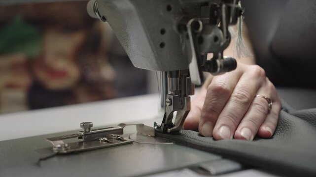 experienced worker works sewing machine. sew leather goods. hands close up. workshop business concept. female hands sew clothes sewing machine. professional seamstress workshop. clothing production