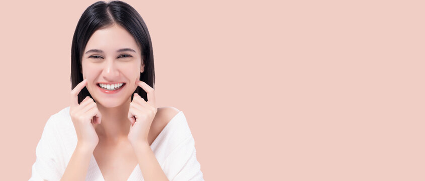 Cheerful young woman with bright smile pointing to cheeks, expressing happiness and confidence. Happy girl get Thooth Whitening  Beautiful woman has beautiful tooth, white teeth, nice tooth alignment.