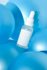 Frosted dropper bottle with white label among blue balloons. Ideal for serums, face oils, and luxury skincare branding. Perfect for cosmetic packaging, e-commerce, and beauty marketing visuals.