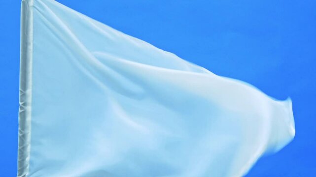 Slow motion video of white flag waving on blue background