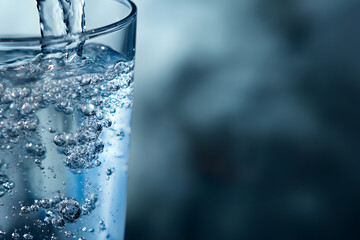 A glass is being filled with clear water, showing bubbles. This highlights the importance of maintaining hydration for kidney. National Kidney Month