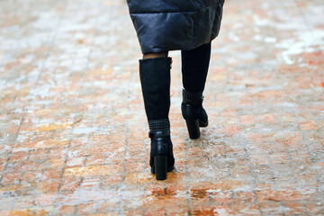 Wet and slushy sidewalk, melting snow creates slippery conditions, winter hazards and the importance of pedestrian safety on icy pavement. Selective focus on icy sidewalk, blured woman boots