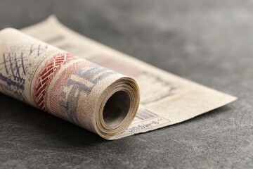 A rolled banknote rests on a textured surface, showcasing its intricate design and details.