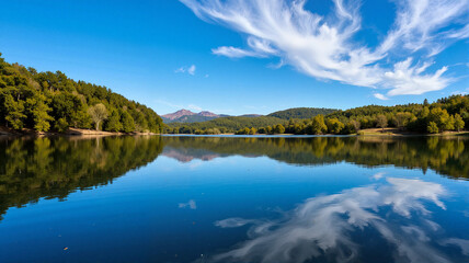 Fototapeta premium Serene lake reflecting sky and mountains in sunlight