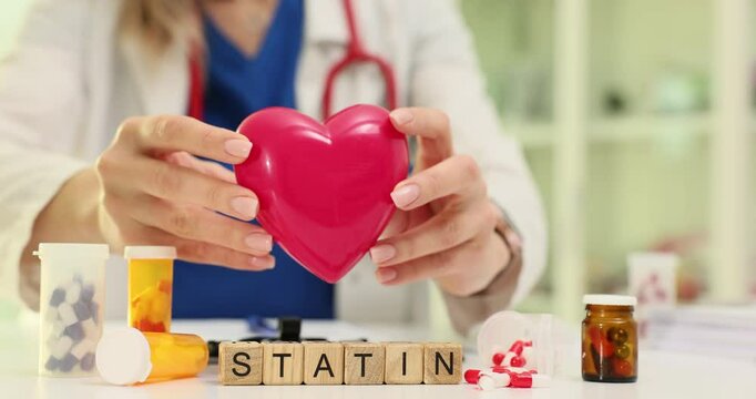 Small wooden cubes neatly arranged in row form word STATIN. Woman doctor explains benefits of statin in preventing plaque buildup in arteries