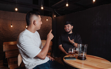 friends talking and laughing at a bar table with beer at night