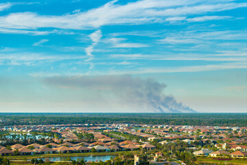 Prescribed fire smoke rising up over suburban neighborhood in Florida