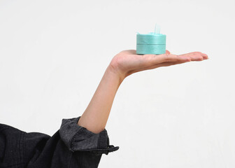 Hand wearing black denim jacket outer holding small round blue gift box object with ribbon on hand...