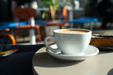 Classic White Coffee Cup on a Café Table. Slow Morning with a Cup of Coffee and Sunlight