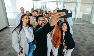 Multiethnic group of colleagues taking a selfie together in an office setting