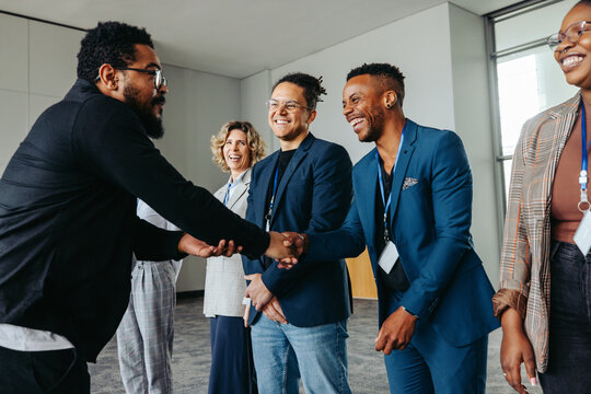 Diverse professionals in a corporate office greeting each other with a handshake - Powered by Adobe