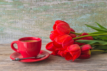 Valentines day concept; bouquet of red tulips and cup of coffee on a old wooden table
