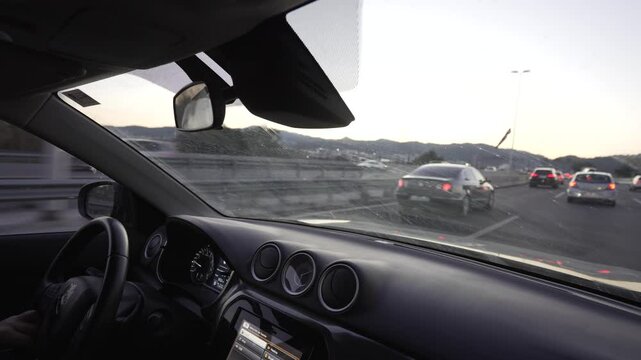 hands on a steering wheel driving in rush hour, heavy but slow-moving traffic