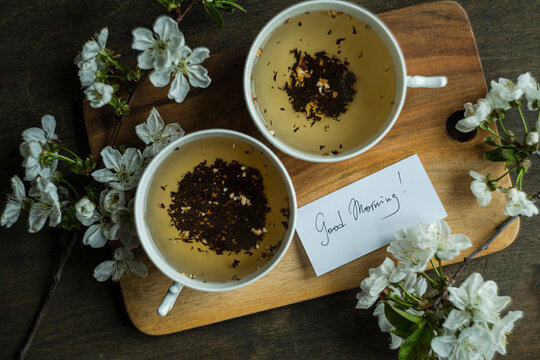 Two cups of black tea and cherry blossoms on wooden table