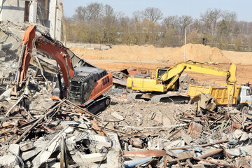 a modern powerful excavator cleans the rubble of a ruined building