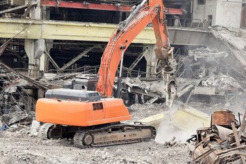 a modern powerful excavator cleans the rubble of a ruined building