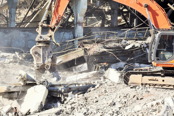 Fototapeta premium a modern powerful excavator cleans the rubble of a ruined building