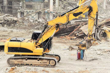 a modern powerful excavator cleans the rubble of a ruined building