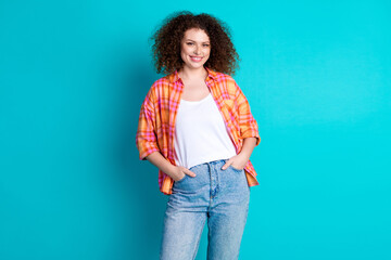 Smiling young woman in casual attire with turquoise background showing confidence and positivity