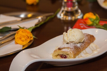 Cherry strudel with ice cream on a white plate.j