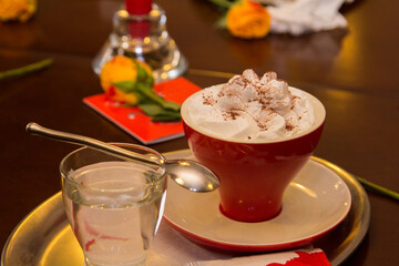 Hot chocolate with whipped cream in a red cup on a wooden table