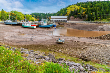 A view across the inlet past boats moored at low tide at Vaughan Creek, New Brunswick in the fall