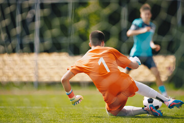 Soccer penalty kick with teen male goalkeeper. Young boy in junior football team saves goal