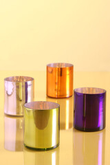 Four colorful and shiny metallic candle holders are reflecting on a gold surface