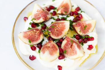 Delicious fig healthy garnished with pomegranate on greek yogurt and virgin olive oil.