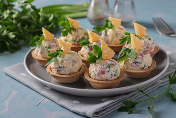 Tartlets with sausage and cheese - delicious holiday snack on gray plate