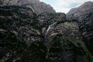 Obraz premium Majestic Mountain Landscape with Cascading Waterfall amidst Lush Greenery..