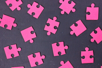 Pink puzzle pieces scattered on dark background