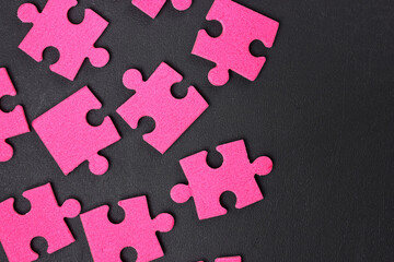 Pink puzzle pieces on a black surface.