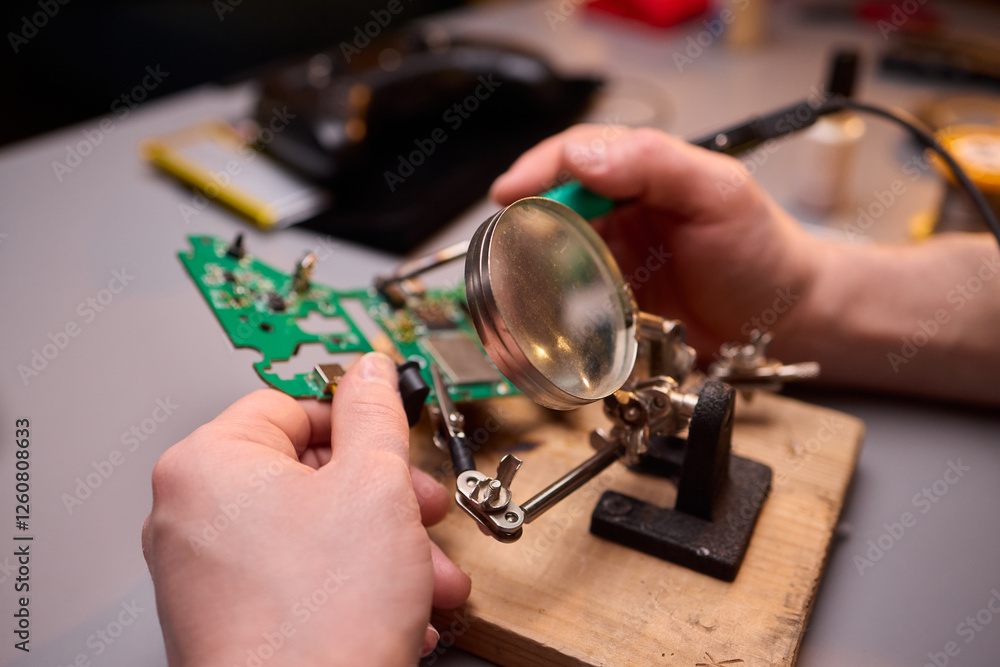 Poster hands carefully repairing a circuit board with a soldering tool for electronics projects