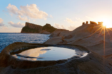 Beautiful sunrise sky reflecting on candle mirror-like rock formations at rocky beach of Yehliu Coastal Geologic Park in northern Taiwan ~ Dramatic scenery of fascinating coastline in northern Taiwan