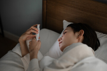 ベッドでスマホを使う女性