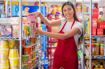 Latina woman, grocery store worker, performs different tasks inside the store. Beautiful Latina...