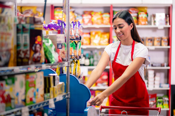 Latina woman, grocery store worker, performs different tasks inside the store. Beautiful Latina...