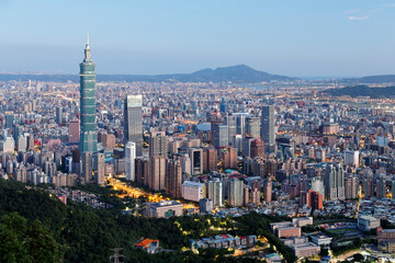Aerial view of Taipei at dusk, the capital city of Taiwan, with 101 Tower standing out in Xinyi Commercial District, ovoid shaped Taipei Dome in nearby area and Tamsui River winding under golden sky