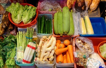 A greengrocer selling fresh, seasonal vegetables and fruits ( lettuce, cucumber, corn, asparagus, ginger, carrot, mushroom )  in Xin-Fu Farmer's Market,Taipei, Taiwan, Asia