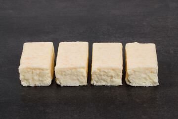 Cottage cheese coconut bar in white chocolate. Dark gray background