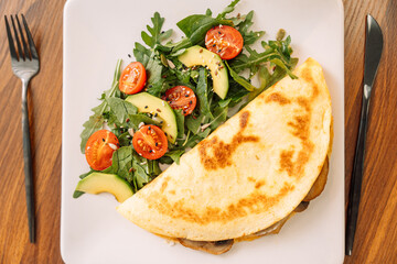 Tortilla with champignons with salad in a square white plate.