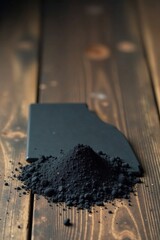 Dark Powder Pile on Dark Wooden Surface with Black Object